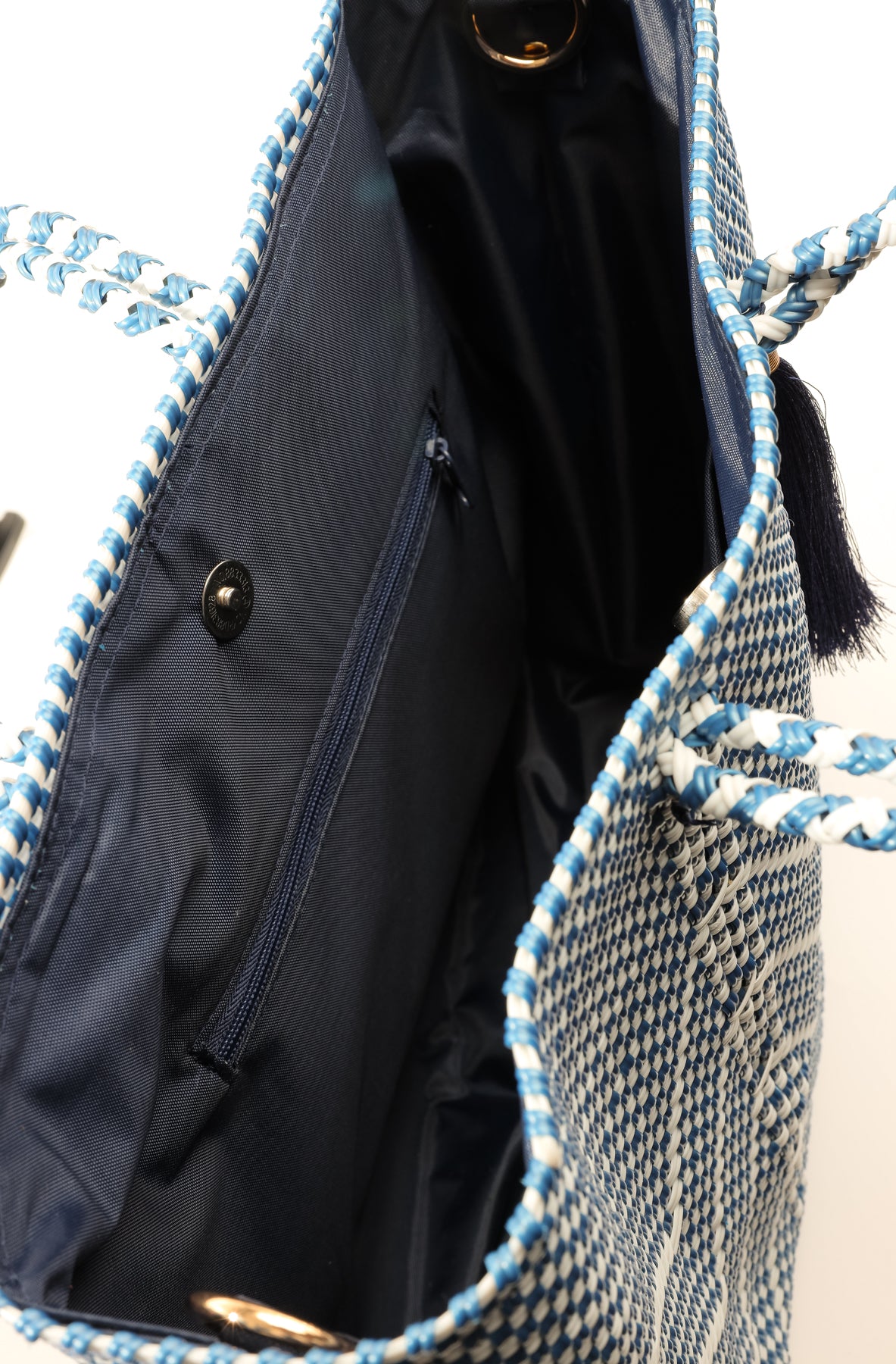 Inside navy blue and white tote with navy blue lining, zipper pocket, and magnetic closure